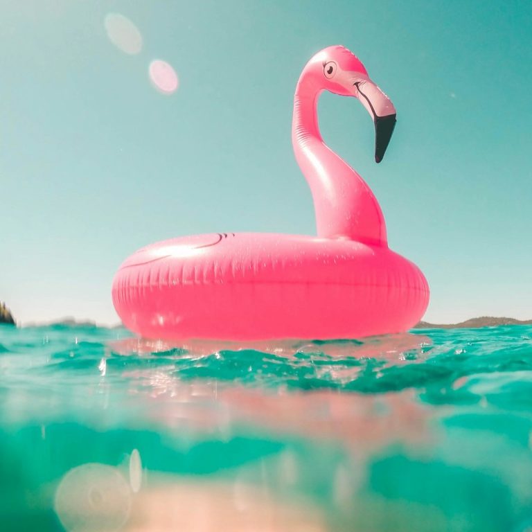Rosa Flamingo-Schwimmring schwimmt im klaren Wasser an einem sonnigen Tag.