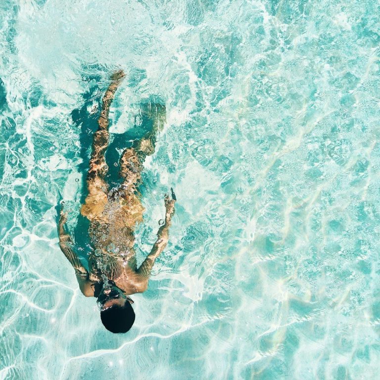 Mann schwimmt entspannt in klarem, türkisfarbenem Wasser.