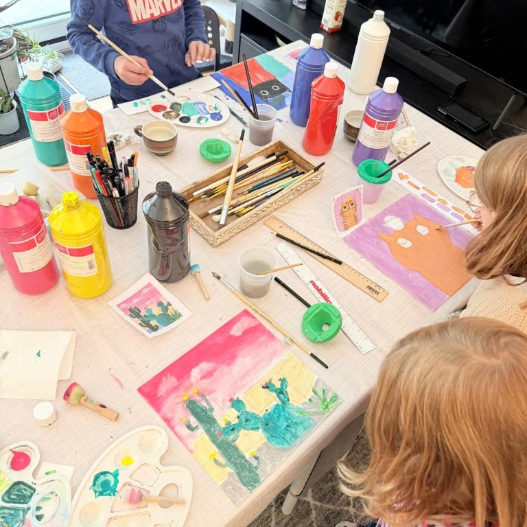 Zwei Kinder sitzen entspannt unter einem Baum, umgeben von herbstlichen Blättern.